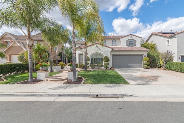 mediterranean / spanish house featuring an attached garage, concrete driveway, a tiled roof, stucco siding, and a front lawn