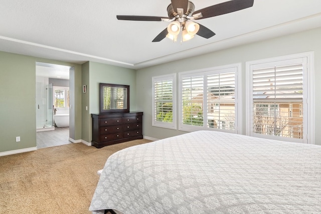 carpeted bedroom with ensuite bathroom, ceiling fan, and baseboards