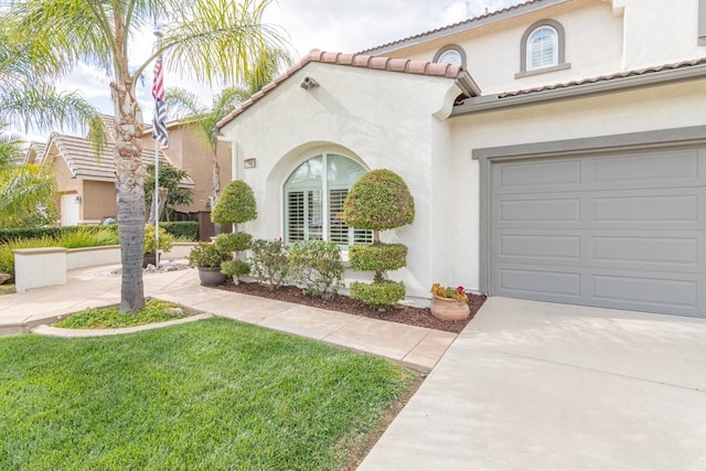 mediterranean / spanish-style house featuring driveway, a tiled roof, a front lawn, and stucco siding