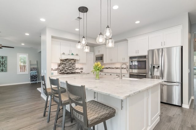 kitchen with light wood-style flooring, decorative backsplash, appliances with stainless steel finishes, white cabinets, and a sink