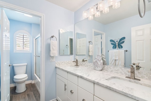 full bathroom featuring toilet, double vanity, a sink, and wood finished floors