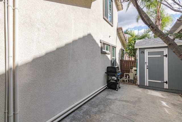 exterior space featuring stucco siding, a storage shed, a patio area, fence, and an outdoor structure