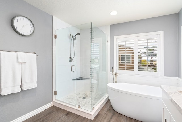 bathroom with a freestanding tub, a stall shower, wood finished floors, and baseboards