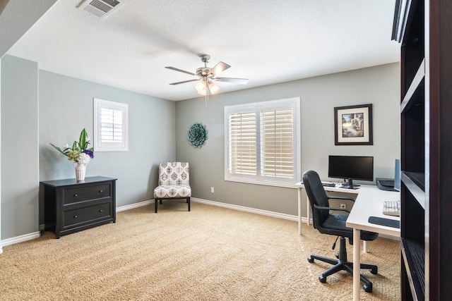 carpeted office space with a ceiling fan, visible vents, a textured ceiling, and baseboards