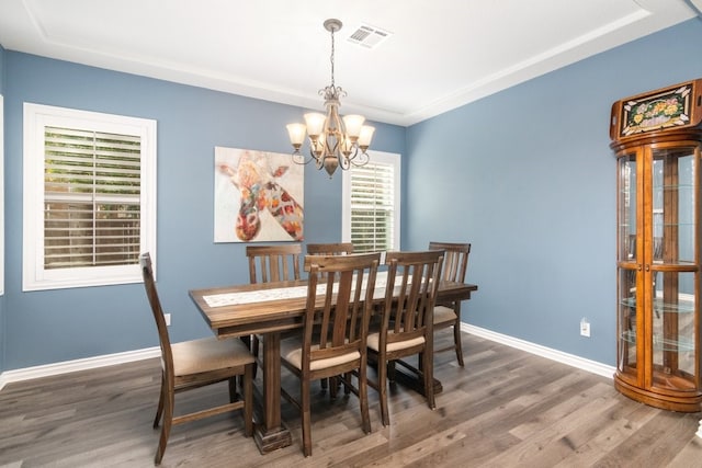 dining space featuring an inviting chandelier, wood finished floors, visible vents, and baseboards