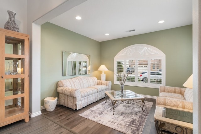 living room featuring baseboards, visible vents, wood finished floors, and recessed lighting