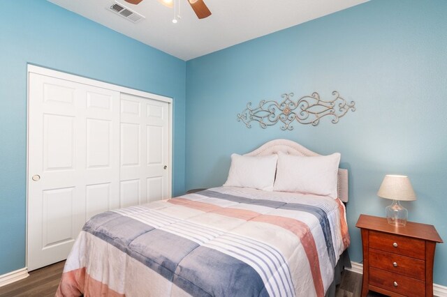 bedroom featuring ceiling fan, wood finished floors, visible vents, baseboards, and a closet