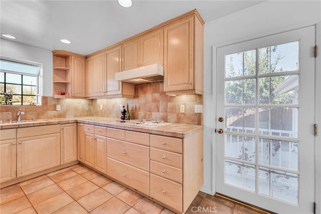 kitchen with under cabinet range hood, light brown cabinets, and a sink