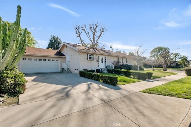 single story home with a garage, driveway, a front yard, and stucco siding