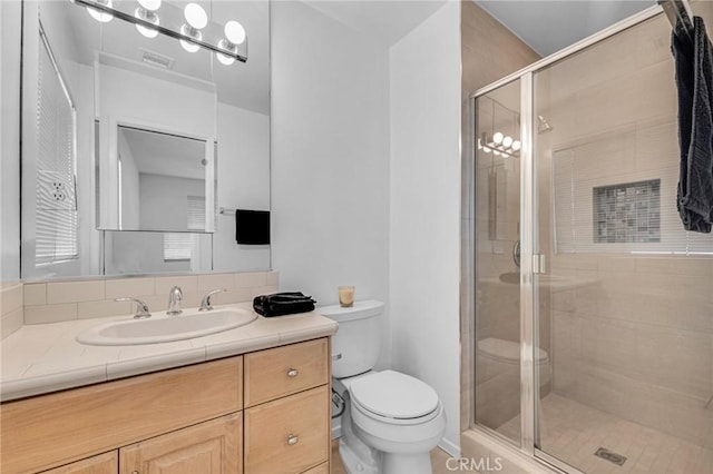 bathroom with visible vents, a shower stall, toilet, and vanity