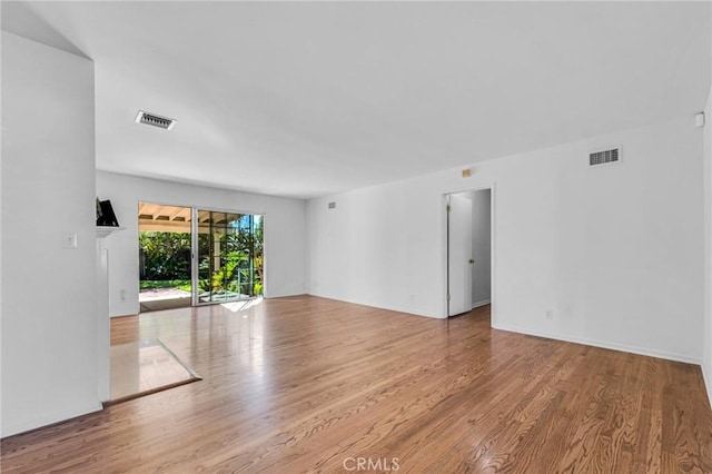 unfurnished room with wood finished floors and visible vents