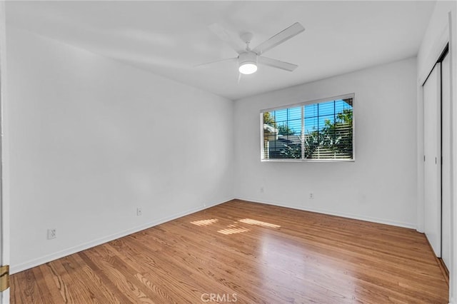 unfurnished bedroom featuring a ceiling fan, light wood-type flooring, a closet, and baseboards