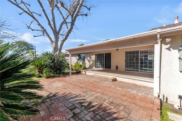 rear view of house featuring a patio and stucco siding