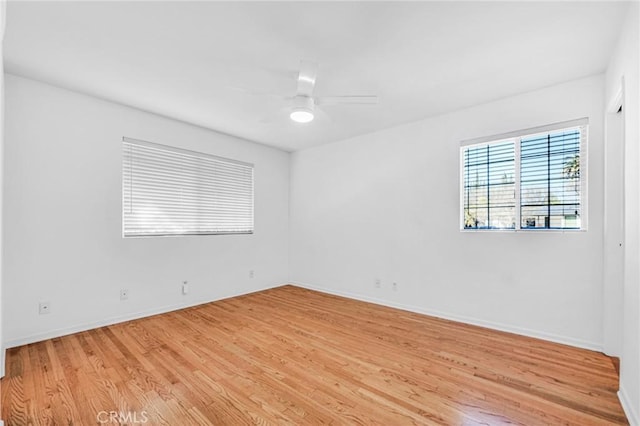 empty room featuring light wood finished floors, ceiling fan, and baseboards