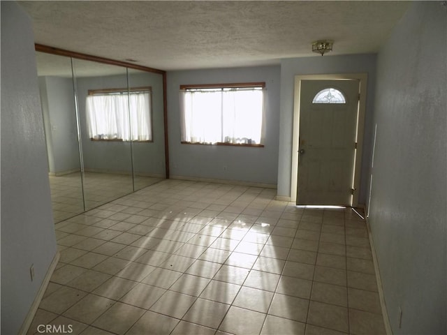 tiled entryway with a textured ceiling and baseboards