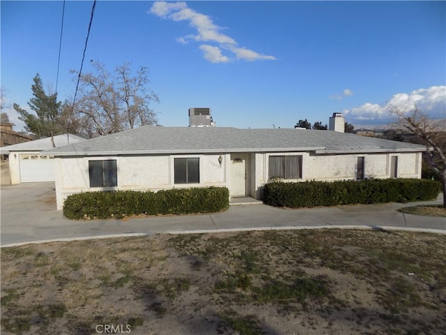 ranch-style house with stucco siding, a garage, concrete driveway, and a chimney