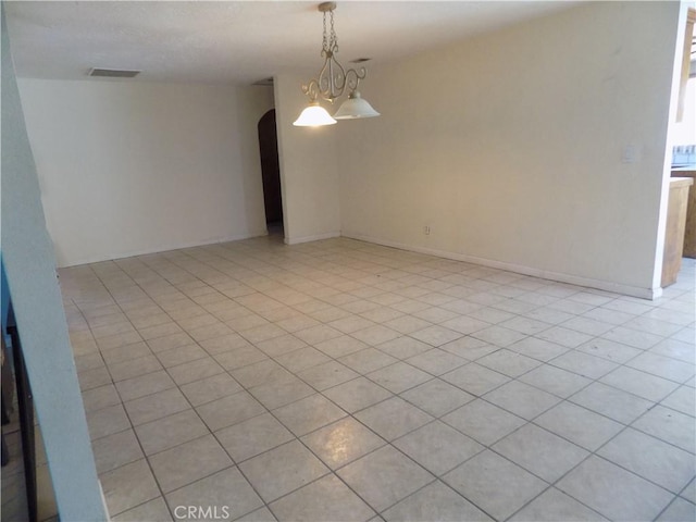 unfurnished room with baseboards, visible vents, arched walkways, and a chandelier