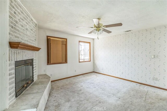 11671 Jacaranda Ave, Hesperia, CA 92345 - unfurnished living room with carpet floors, visible vents, a brick fireplace, ceiling fan, and a textured ceiling