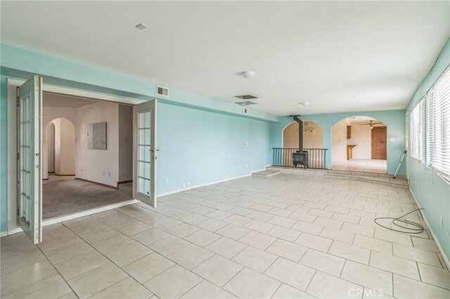 11671 Jacaranda Ave, Hesperia, CA 92345 - spare room featuring visible vents, a wood stove, baseboards, arched walkways, and light tile patterned floors