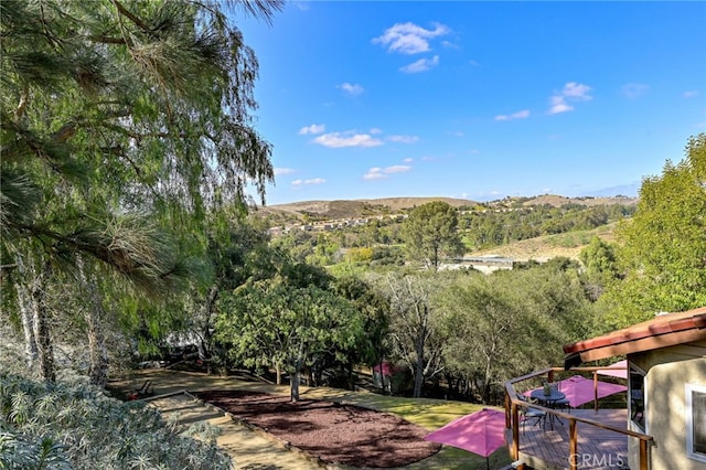 view of yard featuring a deck with mountain view and a forest view