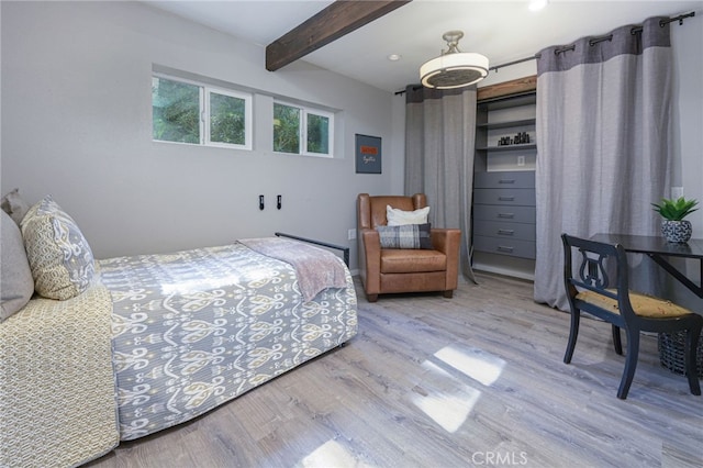 bedroom with beam ceiling and wood finished floors