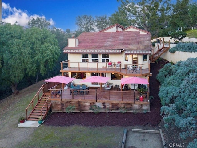 back of property featuring stairs, a tiled roof, a chimney, and a wooden deck