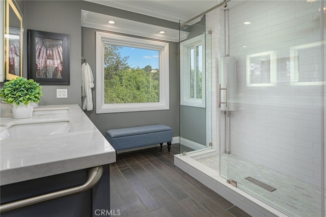 bathroom with a sink, wood tiled floor, crown molding, and a shower stall