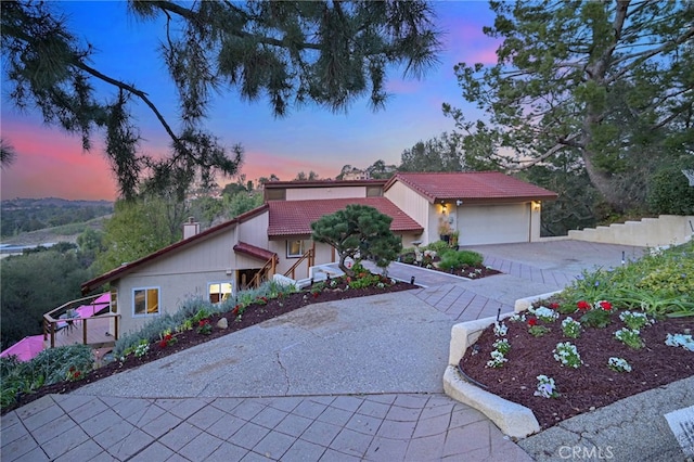 view of front of property featuring decorative driveway, a tile roof, and an attached garage