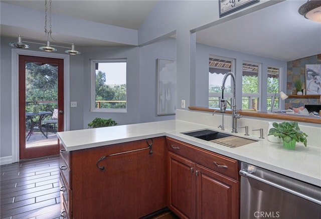 kitchen featuring a peninsula, light countertops, stainless steel dishwasher, pendant lighting, and a sink