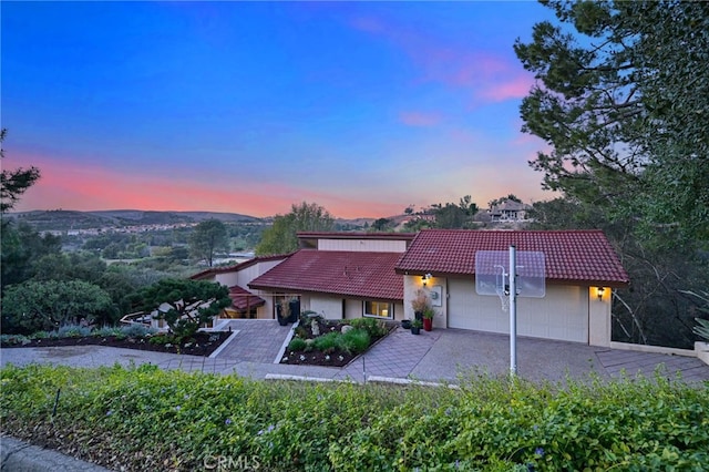 view of front of home with an attached garage, driveway, and a tile roof