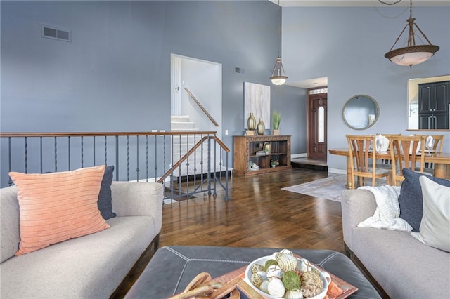 living room featuring stairway, baseboards, visible vents, and wood finished floors