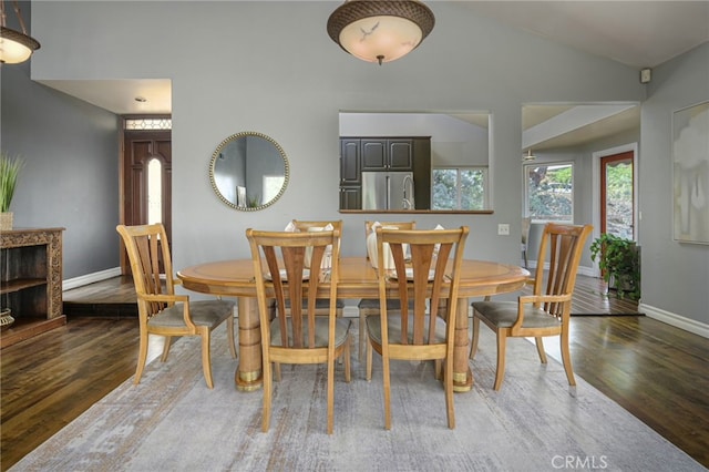 dining area with lofted ceiling, baseboards, and wood finished floors