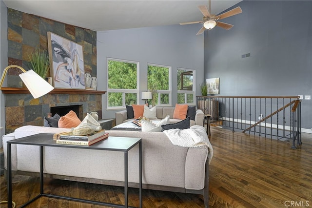 living room featuring visible vents, a ceiling fan, a stone fireplace, wood finished floors, and high vaulted ceiling