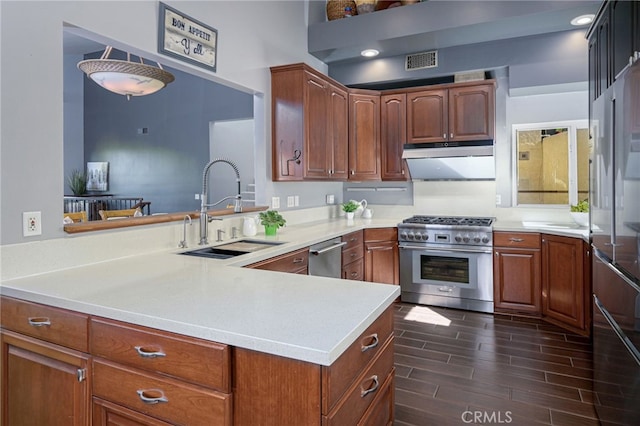 kitchen with wood finish floors, light countertops, appliances with stainless steel finishes, a sink, and under cabinet range hood