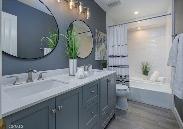 bathroom featuring double vanity, wood finished floors, a sink, and toilet