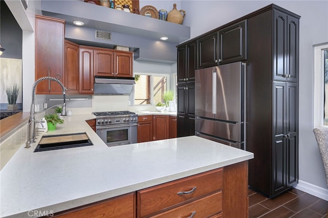 kitchen featuring baseboards, wood tiled floor, stainless steel stove, under cabinet range hood, and a sink