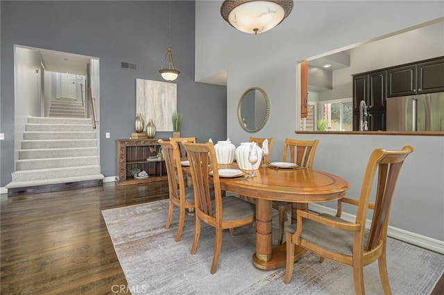 dining space with stairway, wood finished floors, visible vents, and baseboards