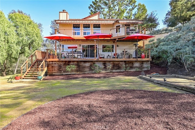 rear view of property featuring a chimney, stairway, and a lawn