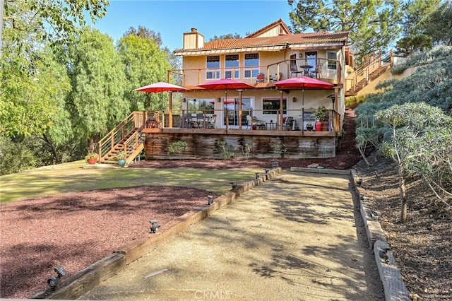 rear view of property featuring stairs, a chimney, and a tile roof