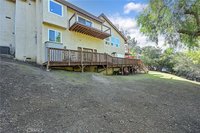 rear view of house with crawl space, a wooden deck, central AC, and stucco siding