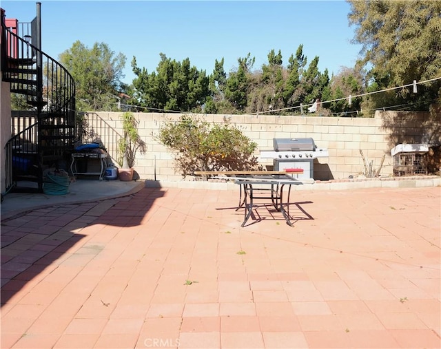 view of patio featuring stairway, grilling area, and fence