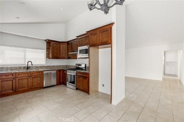 kitchen with lofted ceiling, light stone counters, a sink, appliances with stainless steel finishes, and open shelves