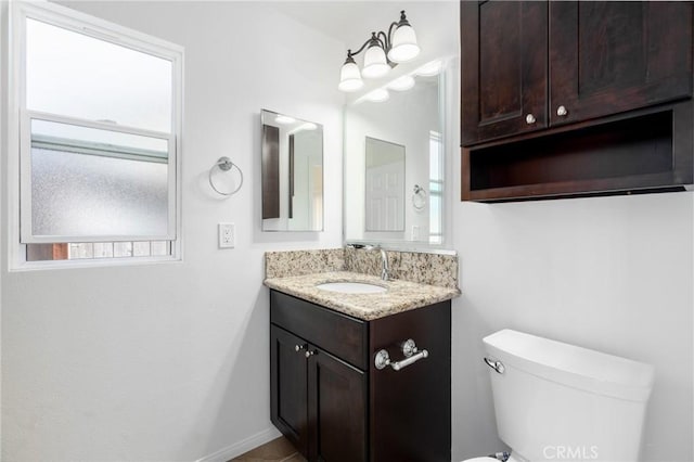 half bathroom featuring baseboards, vanity, and toilet