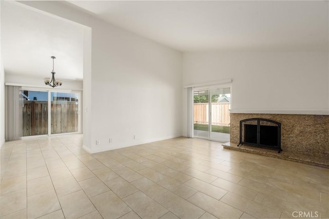 unfurnished living room featuring a chandelier, lofted ceiling, and a fireplace with raised hearth