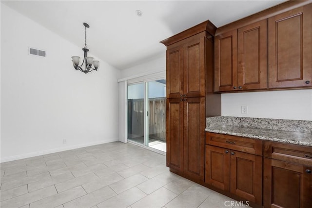 kitchen featuring a chandelier, lofted ceiling, brown cabinets, and visible vents