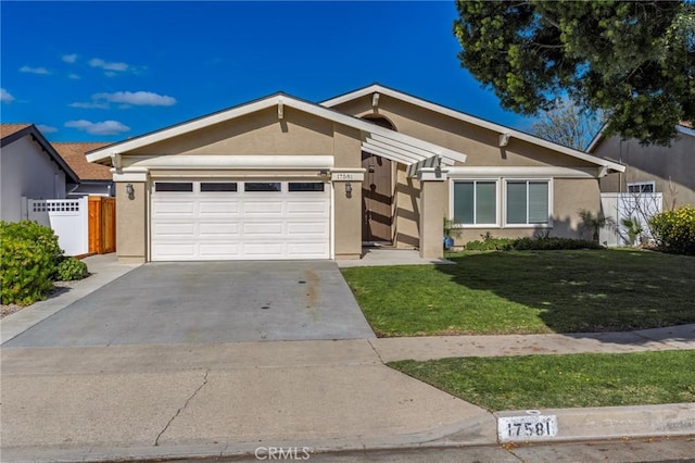 view of front of house with stucco siding, concrete driveway, an attached garage, a front yard, and fence