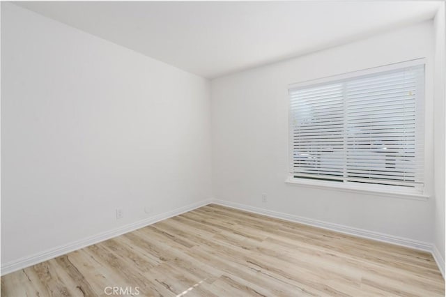 spare room with light wood-style flooring and baseboards