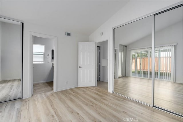 unfurnished bedroom with access to outside, visible vents, vaulted ceiling, and wood finished floors