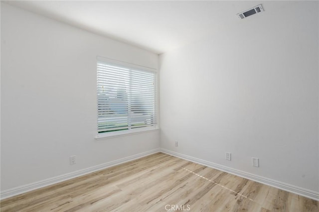 spare room featuring light wood-style floors, baseboards, and visible vents