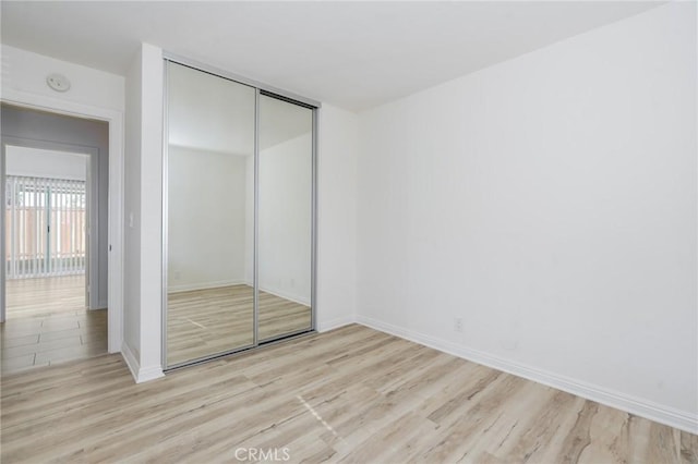 unfurnished bedroom with a closet, baseboards, and wood finished floors